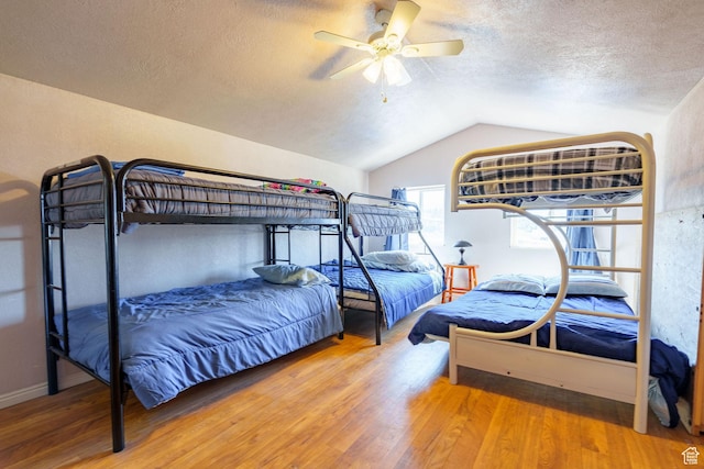 bedroom with a ceiling fan, lofted ceiling, wood finished floors, and a textured ceiling