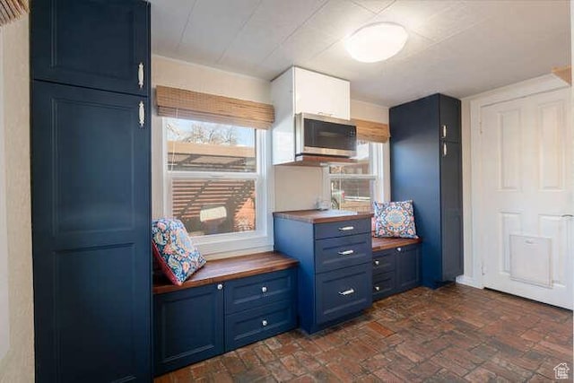 771 E Belmont Ave, Salt Lake City, UT 84105 - kitchen with stainless steel microwave, blue cabinets, brick floor, and butcher block countertops