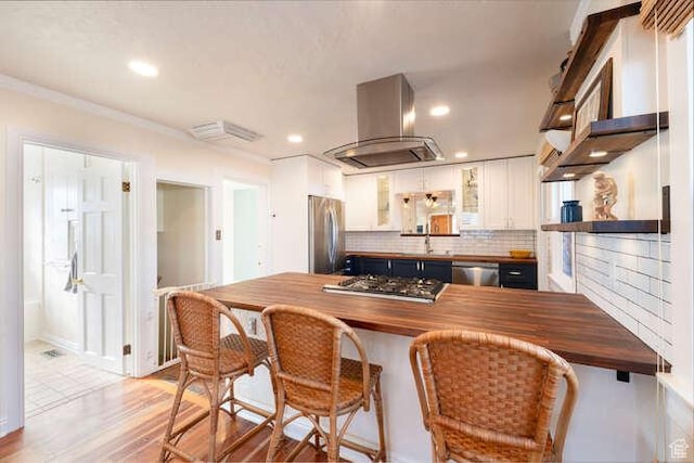 771 E Belmont Ave, Salt Lake City, UT 84105 - kitchen with butcher block countertops, appliances with stainless steel finishes, island range hood, and white cabinetry