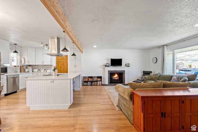living room featuring light wood-style flooring, a fireplace, beamed ceiling, and a textured ceiling