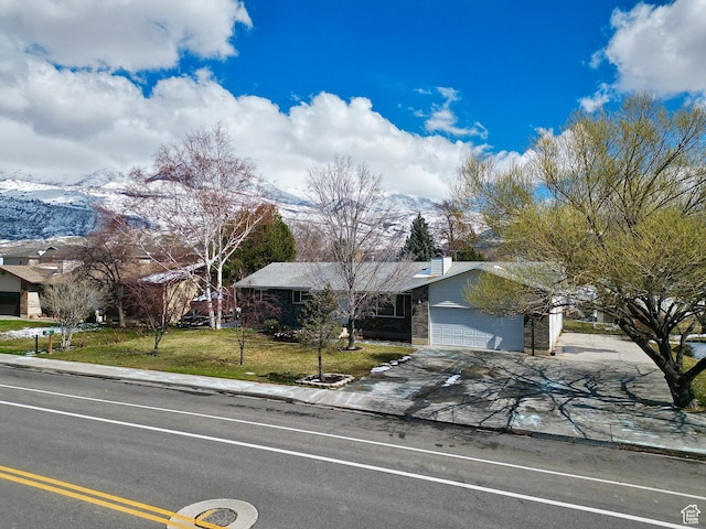 view of front of house with an attached garage, concrete driveway, and a front yard