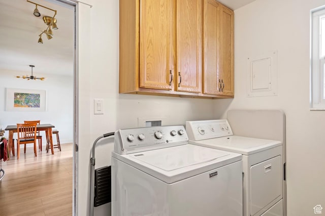 washroom featuring baseboards, washer and dryer, an inviting chandelier, light wood-style floors, and cabinet space