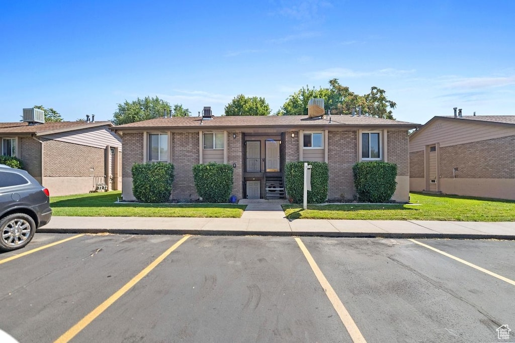 2588 S 900 E Unit 35, Salt Lake City, UT 84106 - view of front of property with brick siding, a front yard, central AC, and uncovered parking
