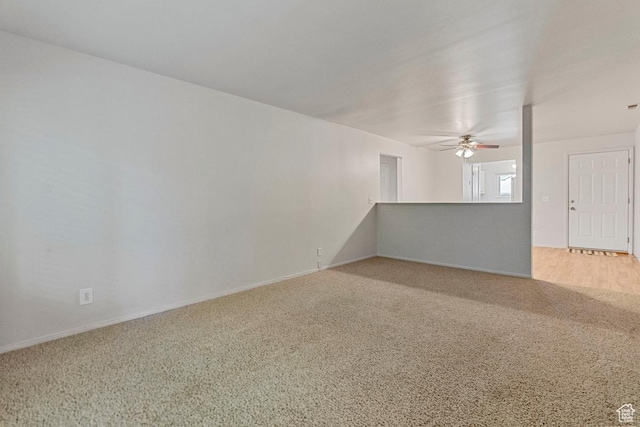 empty room with light colored carpet, baseboards, and ceiling fan