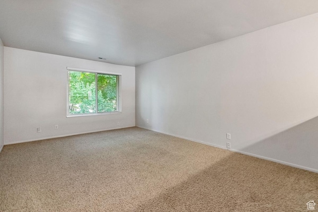 spare room featuring carpet flooring, visible vents, and baseboards