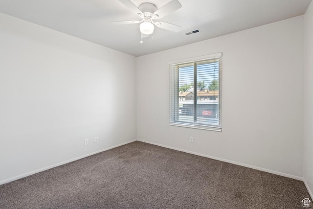 carpeted spare room with visible vents, baseboards, and ceiling fan