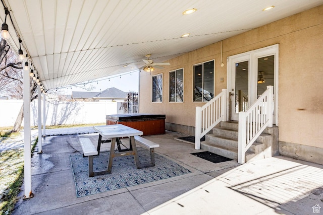 view of patio / terrace featuring a hot tub, outdoor dining area, ceiling fan, and fence