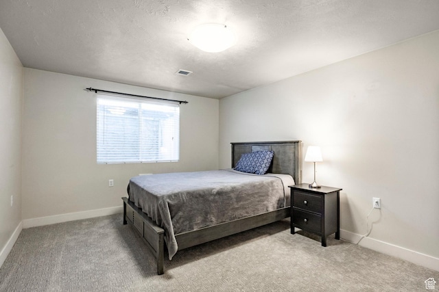 bedroom with a textured ceiling, light colored carpet, visible vents, and baseboards