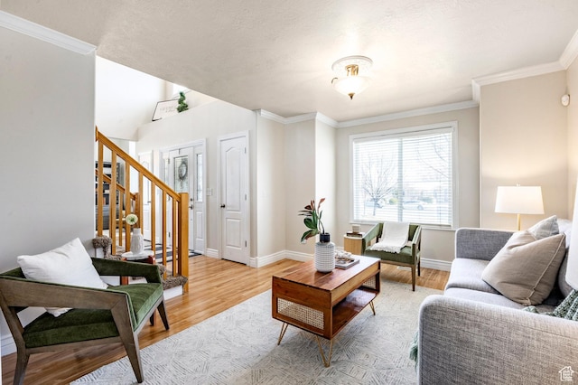 living area with stairway, light wood-style floors, and ornamental molding
