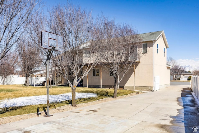view of basketball court with a yard and fence