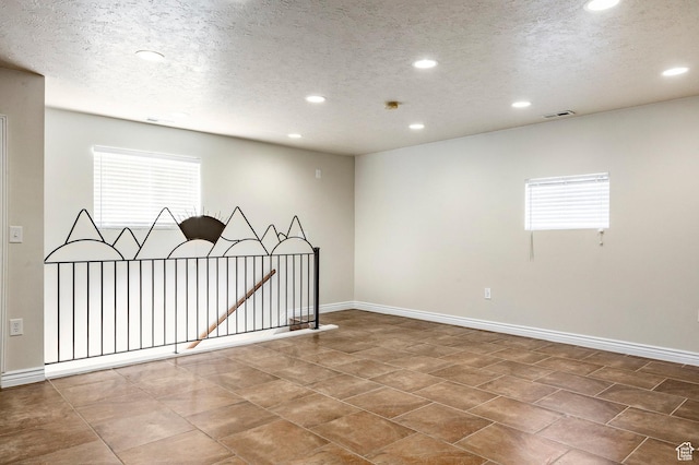 spare room with recessed lighting, visible vents, baseboards, and a textured ceiling