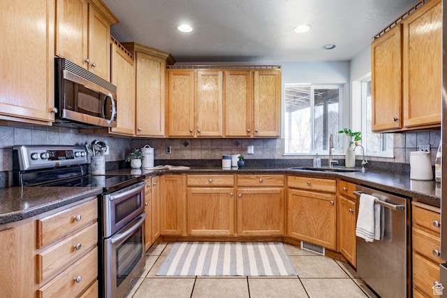 kitchen featuring visible vents, light tile patterned floors, decorative backsplash, stainless steel appliances, and a sink