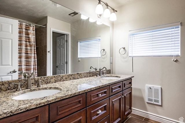 bathroom with double vanity, a shower with curtain, visible vents, and a sink