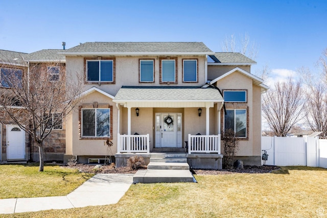 view of front facade featuring a shingled roof, a front yard, fence, and stucco siding