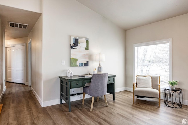 office space with visible vents, baseboards, wood finished floors, and vaulted ceiling
