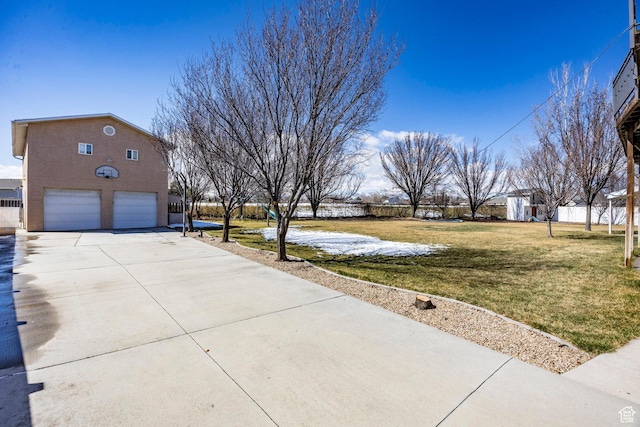 exterior space with stucco siding, a detached garage, a lawn, and concrete driveway