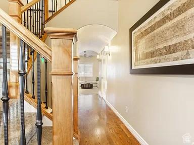 hall with stairway, baseboards, wood finished floors, and a towering ceiling