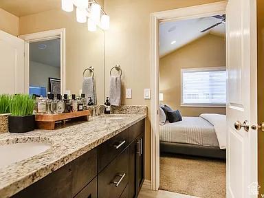 bathroom with a sink, lofted ceiling, ensuite bath, and double vanity