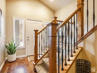 entryway featuring baseboards, wood finished floors, stairs, and vaulted ceiling
