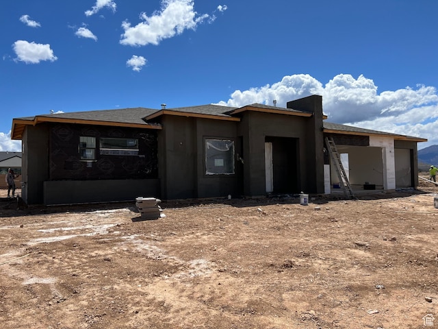 rear view of property with an attached garage and stucco siding