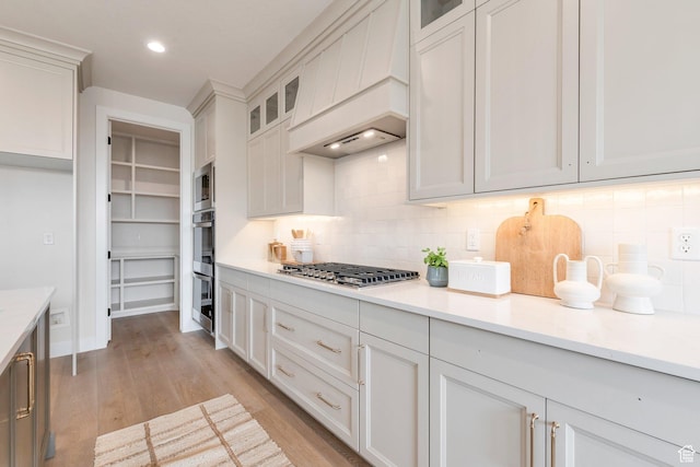 2123 N 520 W, Centerville, UT 84014 - kitchen featuring light countertops, light wood-style flooring, stainless steel gas stovetop, backsplash, and custom exhaust hood