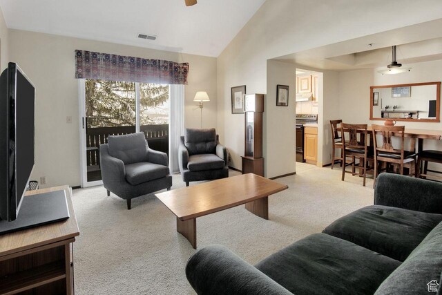 living area with visible vents, light colored carpet, and lofted ceiling