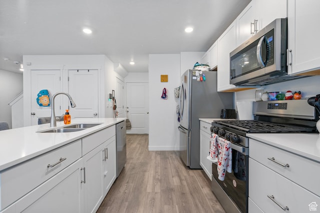 1027 E Reef Dr, Saratoga Springs, UT 84045 - kitchen with light countertops, light wood-type flooring, appliances with stainless steel finishes, white cabinets, and a sink