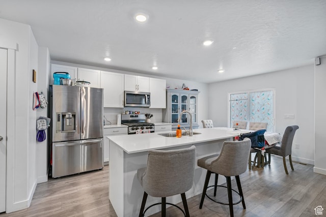 1027 E Reef Dr, Saratoga Springs, UT 84045 - kitchen with a breakfast bar area, a sink, stainless steel appliances, light countertops, and light wood-style floors
