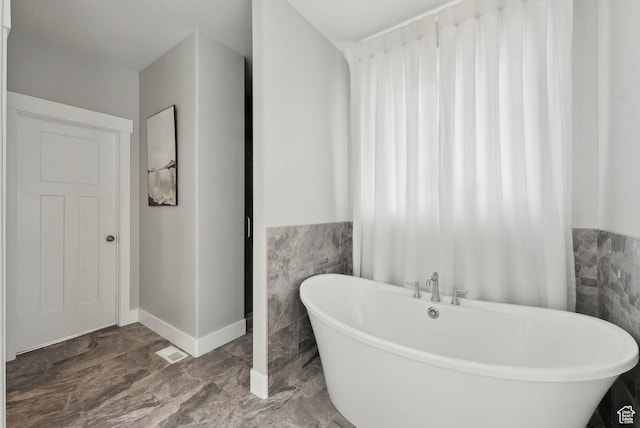 9227 N Horizon Dr, Eagle Mountain, UT 84005 - bathroom featuring a soaking tub, tile walls, and wainscoting