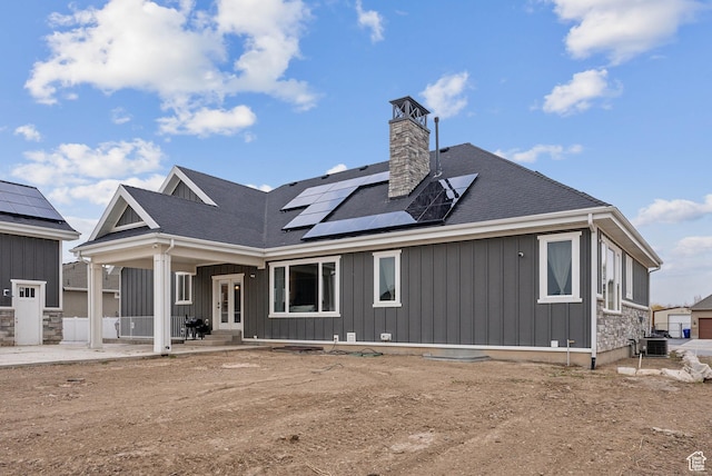 9227 N Horizon Dr, Eagle Mountain, UT 84005 - back of property featuring roof mounted solar panels, central AC, french doors, board and batten siding, and a chimney