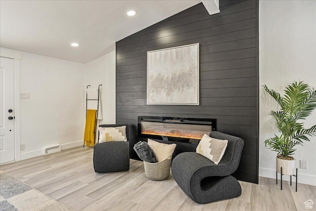 living area featuring visible vents, baseboards, recessed lighting, vaulted ceiling, and wood finished floors