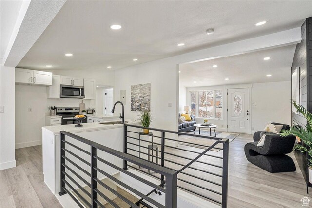 7046 S 2955 E, Cottonwood Heights, UT 84121 - kitchen featuring a sink, white cabinets, light wood-type flooring, and stainless steel appliances