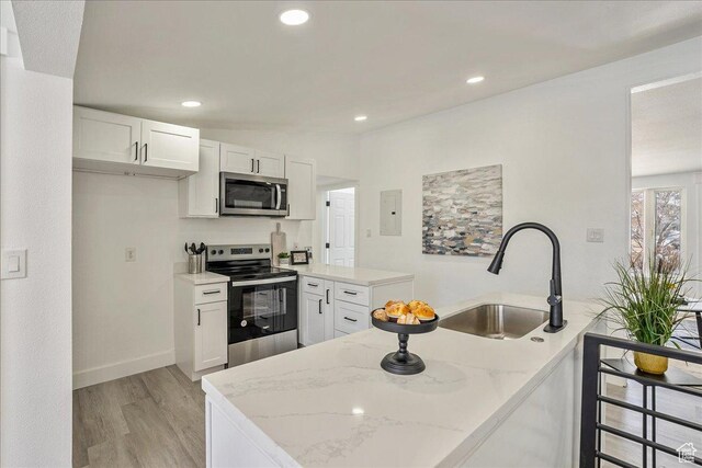 7046 S 2955 E, Cottonwood Heights, UT 84121 - kitchen with white cabinetry, light stone counters, a sink, stainless steel appliances, and light wood finished floors