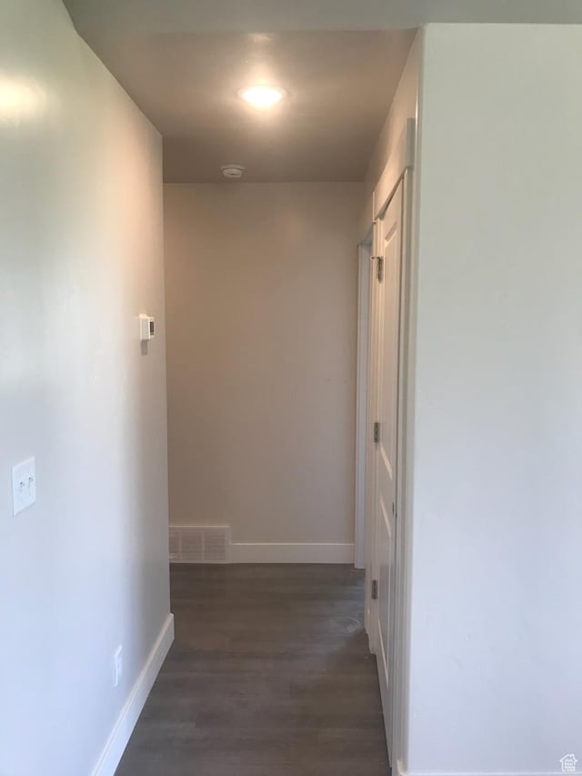 corridor featuring visible vents, baseboards, and dark wood-type flooring