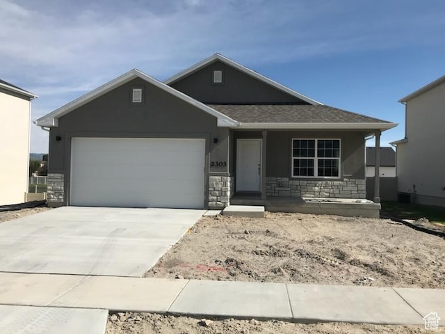 ranch-style home featuring an attached garage, stone siding, driveway, and stucco siding