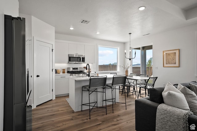 336 W Rosie Loop Unit 45W, Cedar City, UT 84721 - kitchen featuring appliances with stainless steel finishes, open floor plan, a kitchen bar, wood finished floors, and light countertops