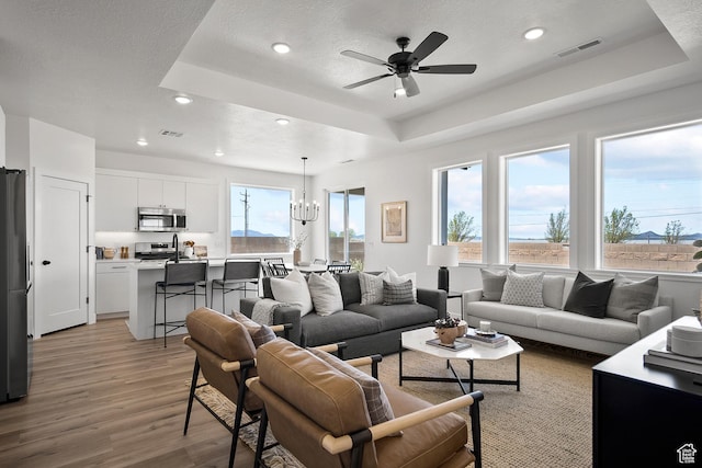 336 W Rosie Loop Unit 45W, Cedar City, UT 84721 - living room with a raised ceiling, light wood finished floors, a chandelier, recessed lighting, and ceiling fan