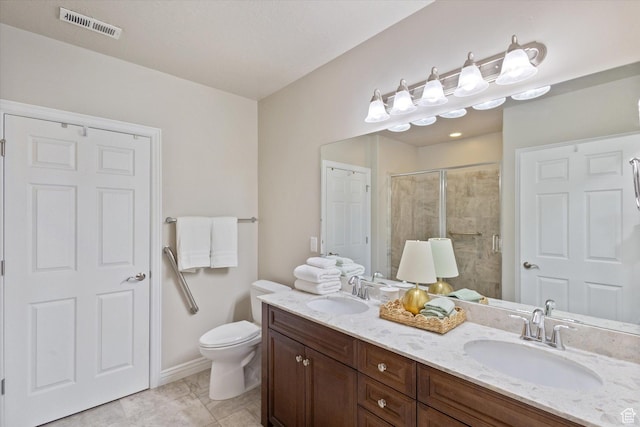 bathroom featuring a shower stall, toilet, and double vanity