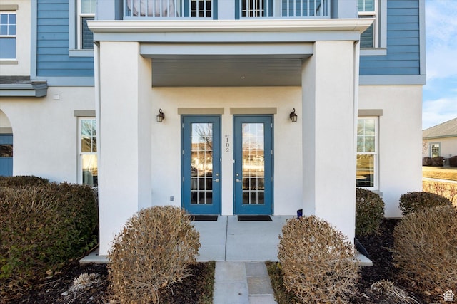 property entrance with stucco siding and french doors