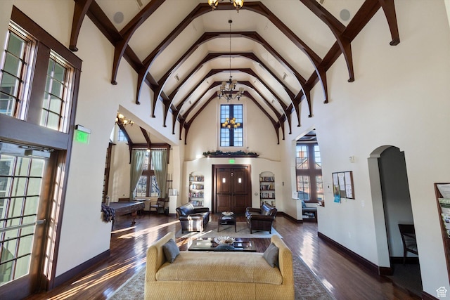 living area featuring high vaulted ceiling, a chandelier, hardwood / wood-style flooring, arched walkways, and baseboards