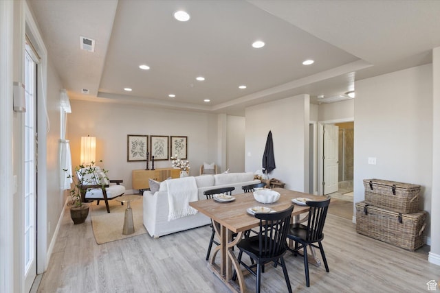 dining room with a tray ceiling, light wood-style flooring, baseboards, and recessed lighting