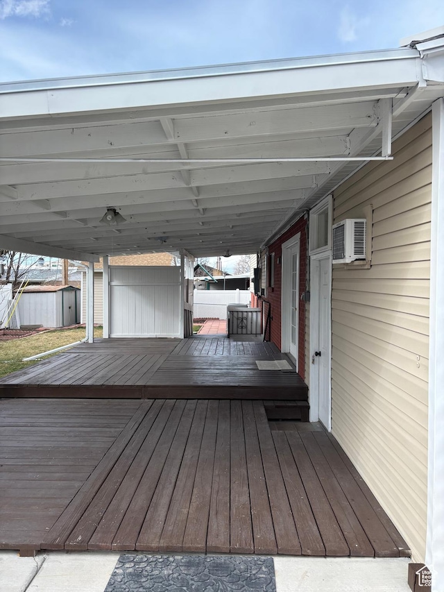 wooden deck featuring a storage unit, an outdoor structure, and a wall mounted air conditioner