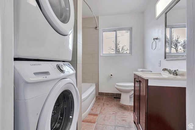full bath featuring stacked washer / drying machine, vanity, baseboards, tile patterned floors, and toilet