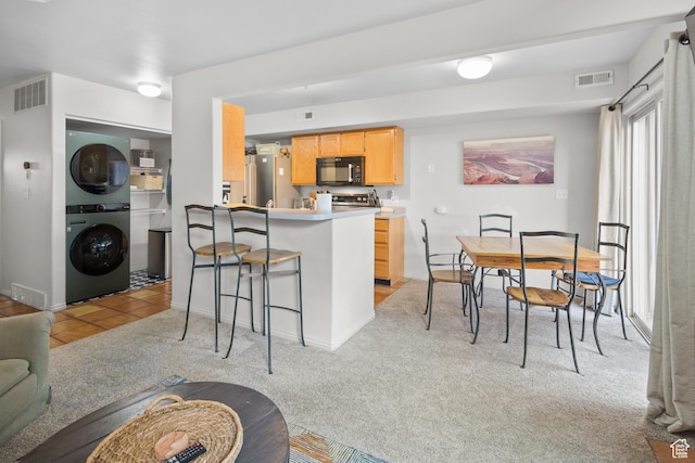 3354 E Fairway Loop, Moab, UT 84532 - kitchen featuring visible vents, black microwave, light colored carpet, and stacked washer / drying machine