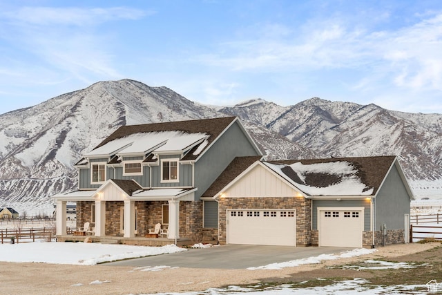 view of front of house with stone siding, fence, an attached garage, concrete driveway, and covered porch