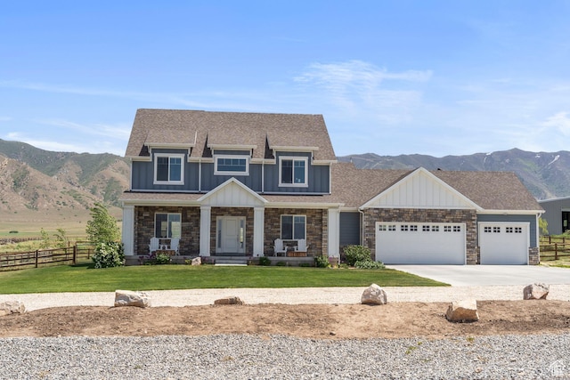 2558 Mountain Glen Rd, Erda, UT 84074 - view of front of home featuring board and batten siding, a mountain view, an attached garage, concrete driveway, and covered porch