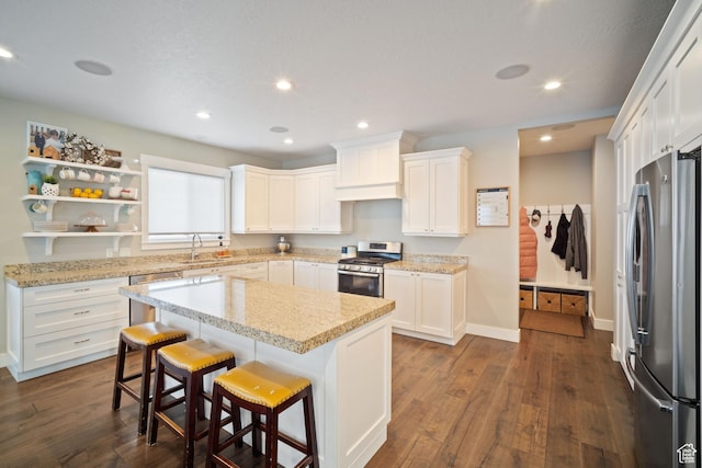 2558 Mountain Glen Rd, Erda, UT 84074 - kitchen with appliances with stainless steel finishes, dark wood-style floors, white cabinets, a breakfast bar, and a kitchen island