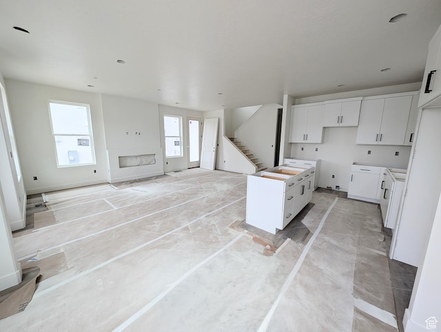 7077 W Granbury Dr S Unit 257, South Jordan, UT 84009 - kitchen with white cabinetry, open floor plan, a center island, and baseboards