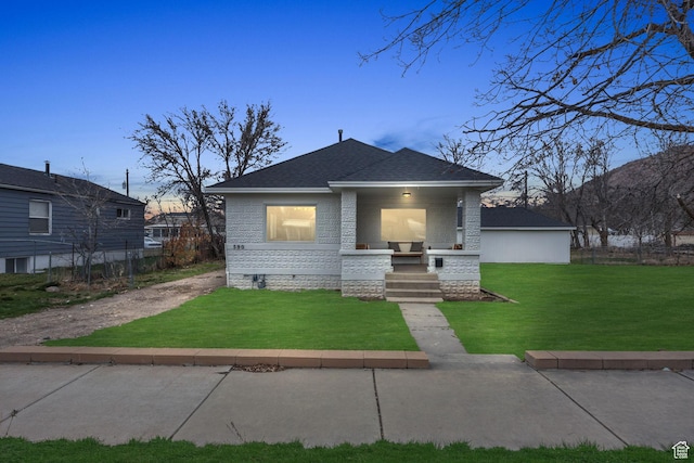view of front of home featuring a lawn, covered porch, and roof with shingles