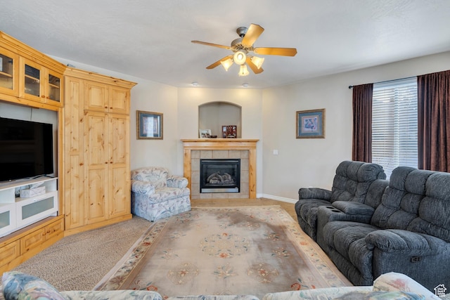 living area with baseboards, a ceiling fan, carpet, and a tile fireplace